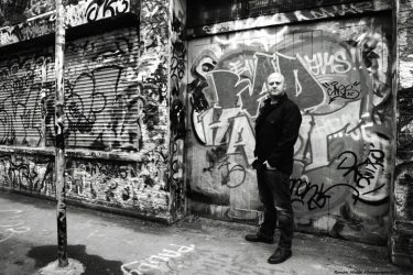 photo of andrew strong next to graffiti wall