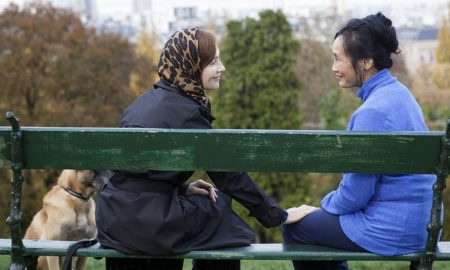 women sitting together on park bench
