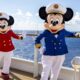 Minnie Mouse and Mickey Mouse standing on the deck of the Disney Cruise Ship, with the ocean in the background.