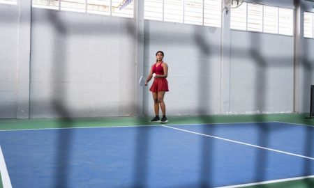 Young woman playing pickleball, holding paddle and getting ready to serve