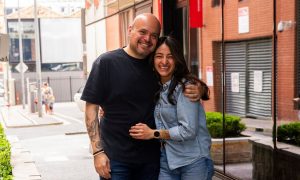 Alejandro Huerta and Galia Valadez stand arm in arm on the footpath under Barro’s neon sign