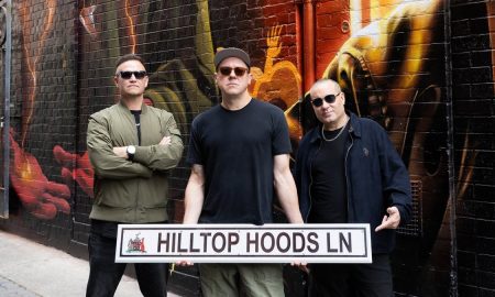 The three members of Hilltop Hoods holding a Hilltop Hoods Ln street sign in the painted laneway
