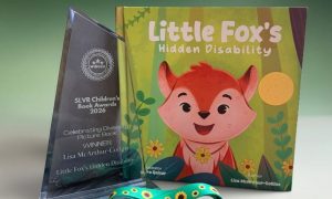 The picture book Little Fox’s Hidden Disability standing beside a glass SLVR award and a green sunflower lanyard