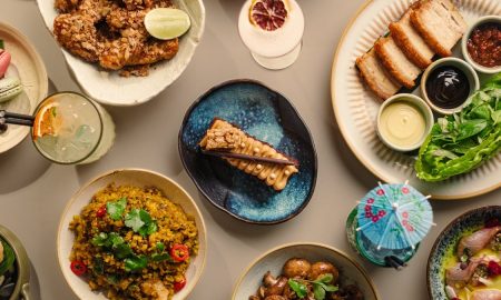 Overhead spread of Paper Tiger dishes including fried chicken, crispy pork belly, fried rice, sashimi, desserts and cocktails